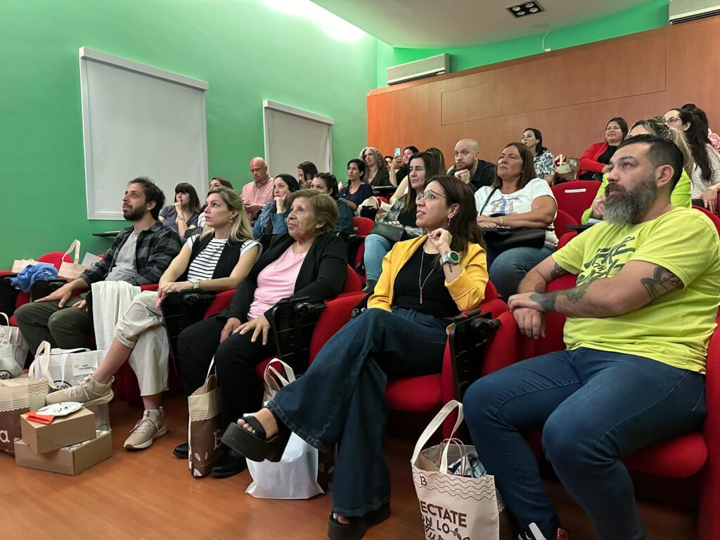 Personas sentadas en unas butacas que miran hacia la pantalla de un proyector