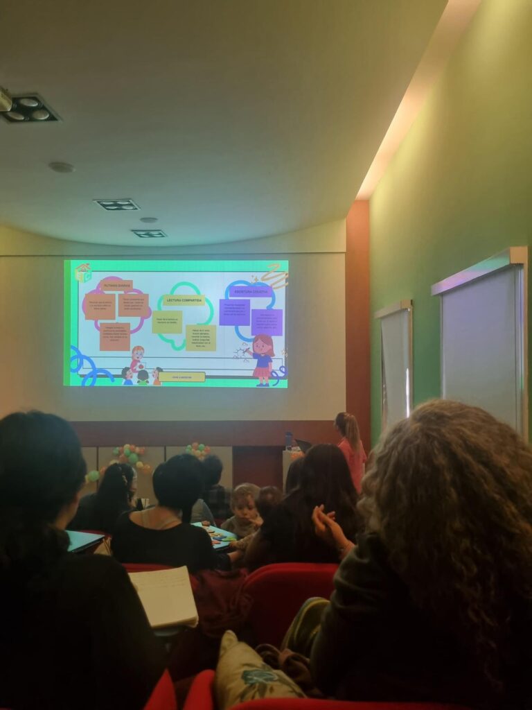 Personas sentadas en unas butacas mirando a una pantalla con proyector