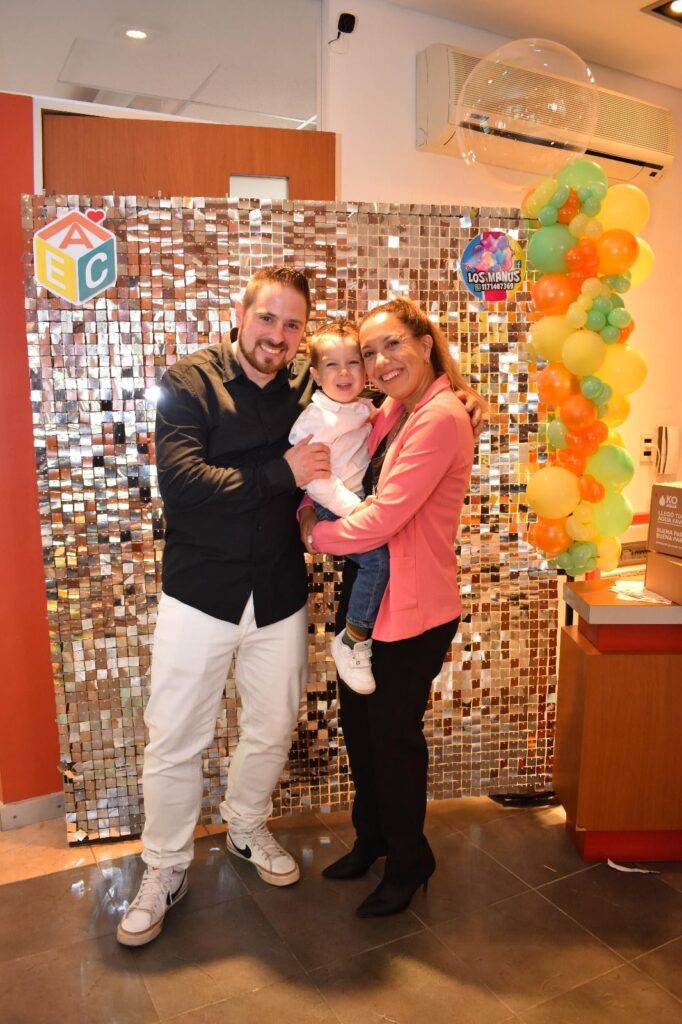 Michele, Giselle y Stefano en posa para una foto delante de un panel brillante